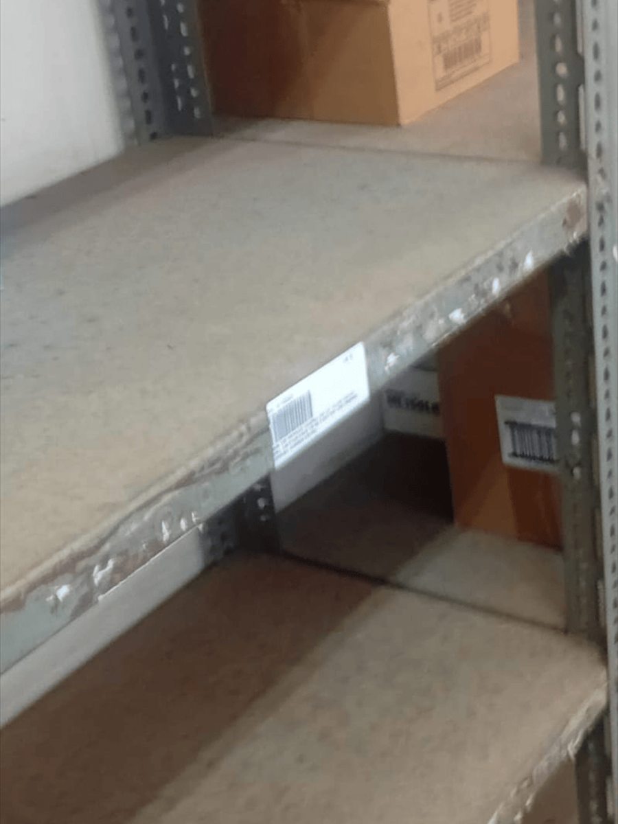 Warehouse shelving before painting, with bare board shelves and paint-spattered frames