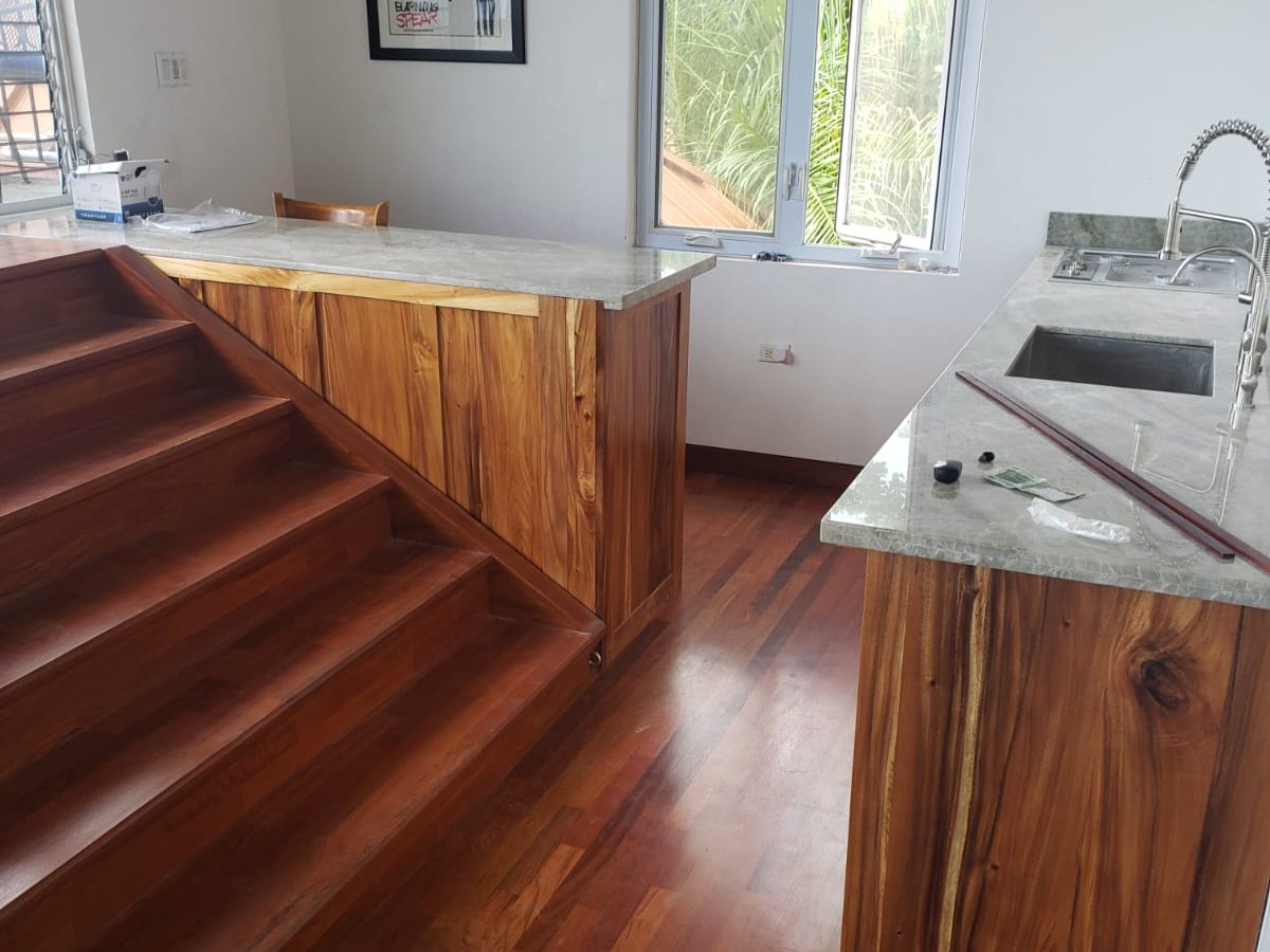 Hardwood staircase and matching floor installed through an open-plan kitchen