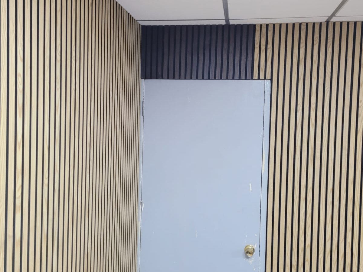 Wood slat wall panelling run around a doorway in two tones